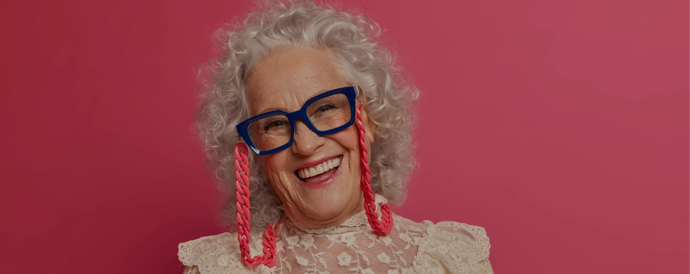 Close-up of an elegant elderly woman wearing stylish clothes, looking confident and graceful against a plain background.